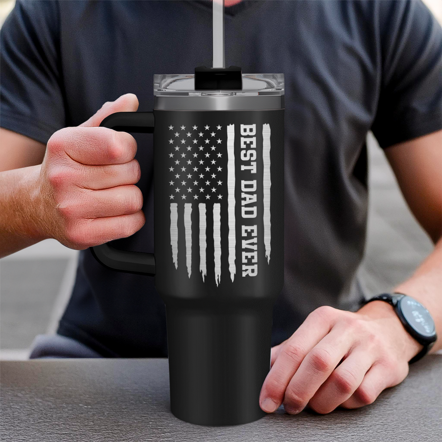 Black 40oz tumbler with handle and Dad flag design, held by hands