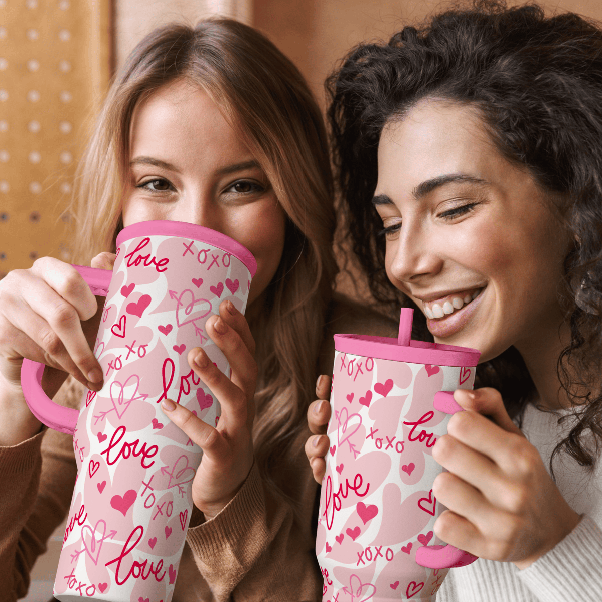 Two pink 40oz tumblers with handles, white bodies with pink hearts and love pattern.