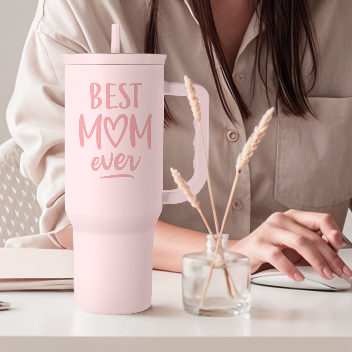 Pink 40oz tumbler with handle, 'Best Mom ever' print and straw, on table