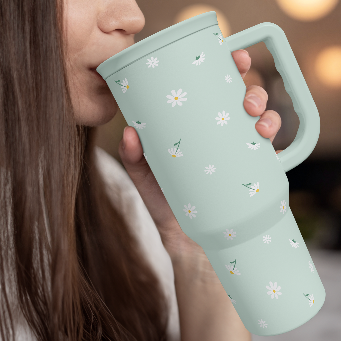 Mint daisy 40oz tumbler with handle held to mouth with straw