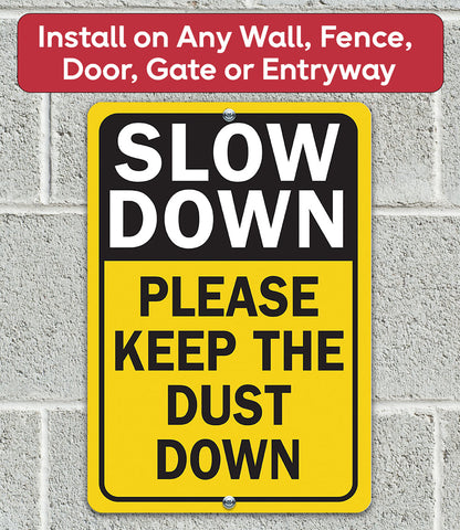Square yellow metal dust sign reading “SLOW DOWN” and “PLEASE KEEP THE DUST DOWN”