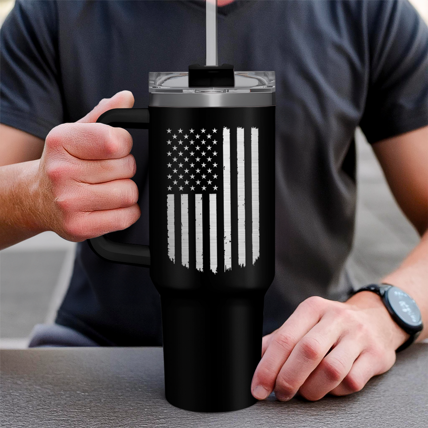 Black 40oz tumbler with handle and American flag print held in hands