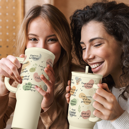 Beige printed inspiration tumbler with straw, held by two people