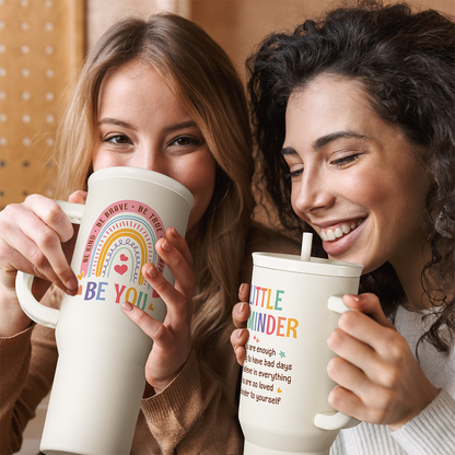 White 40oz slider tumbler with handle; “BE YOU” rainbow heart print on front.