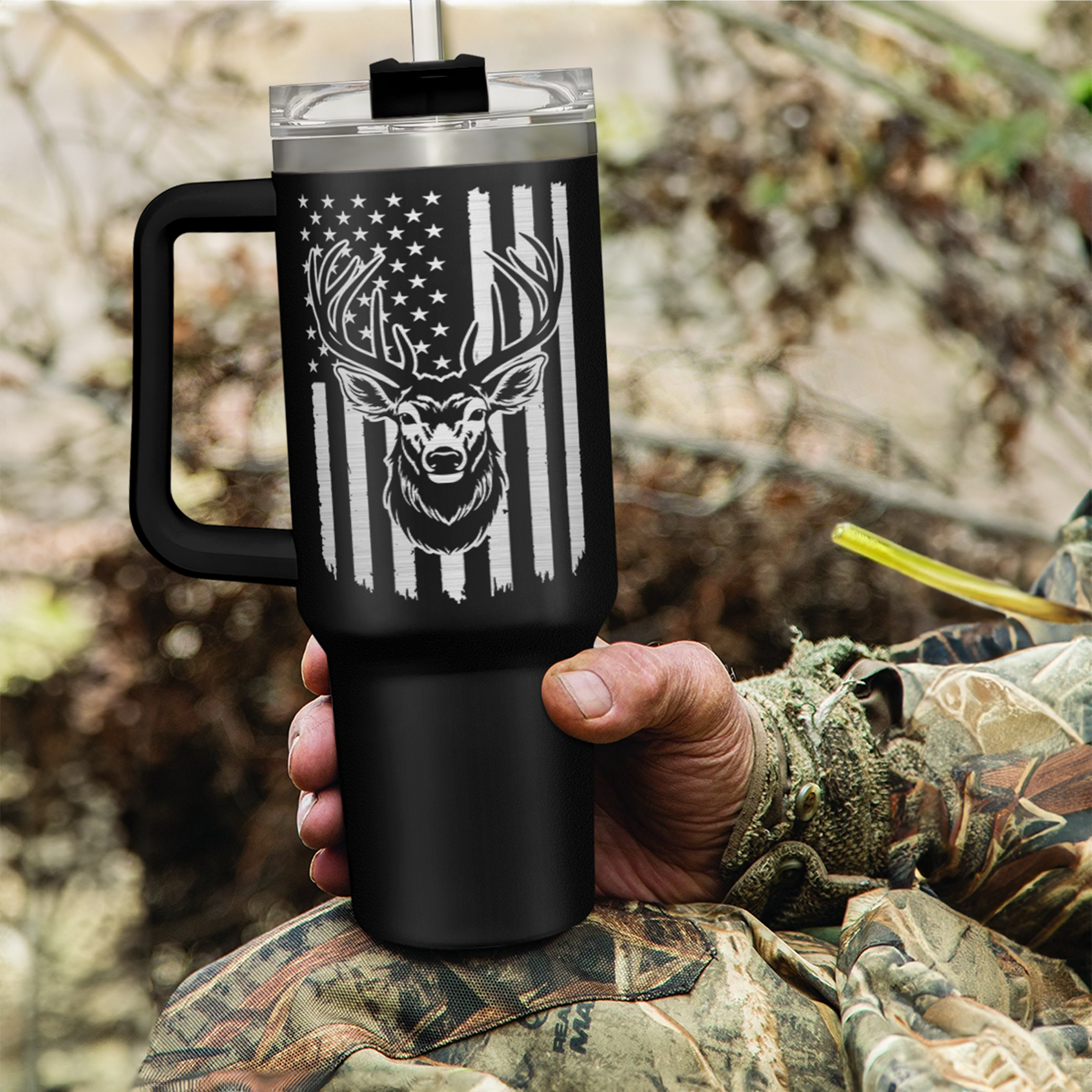 Black 40oz insulated tumbler with handle and deer antler flag graphic, held in hand