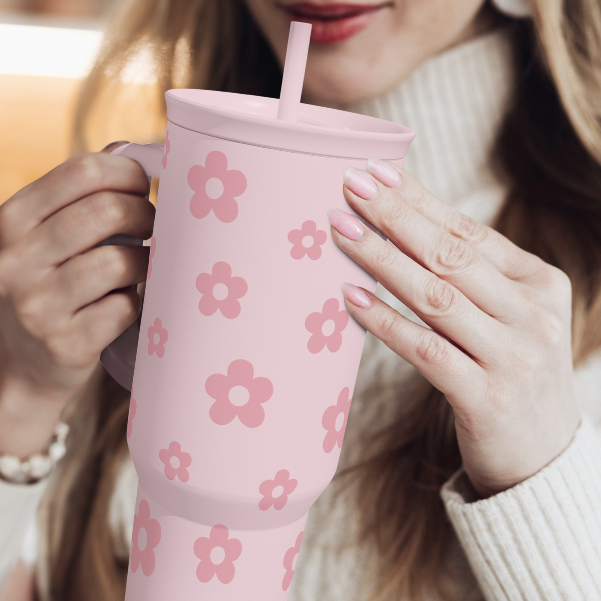 Pink floral tumbler with straw, held in hands