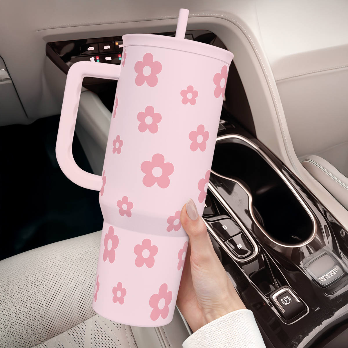 Pink floral tumbler with handle in car seat area near center console