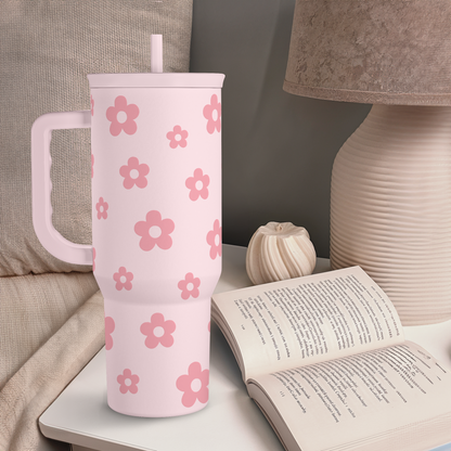 Pink floral tumbler with straw on nightstand beside an open book