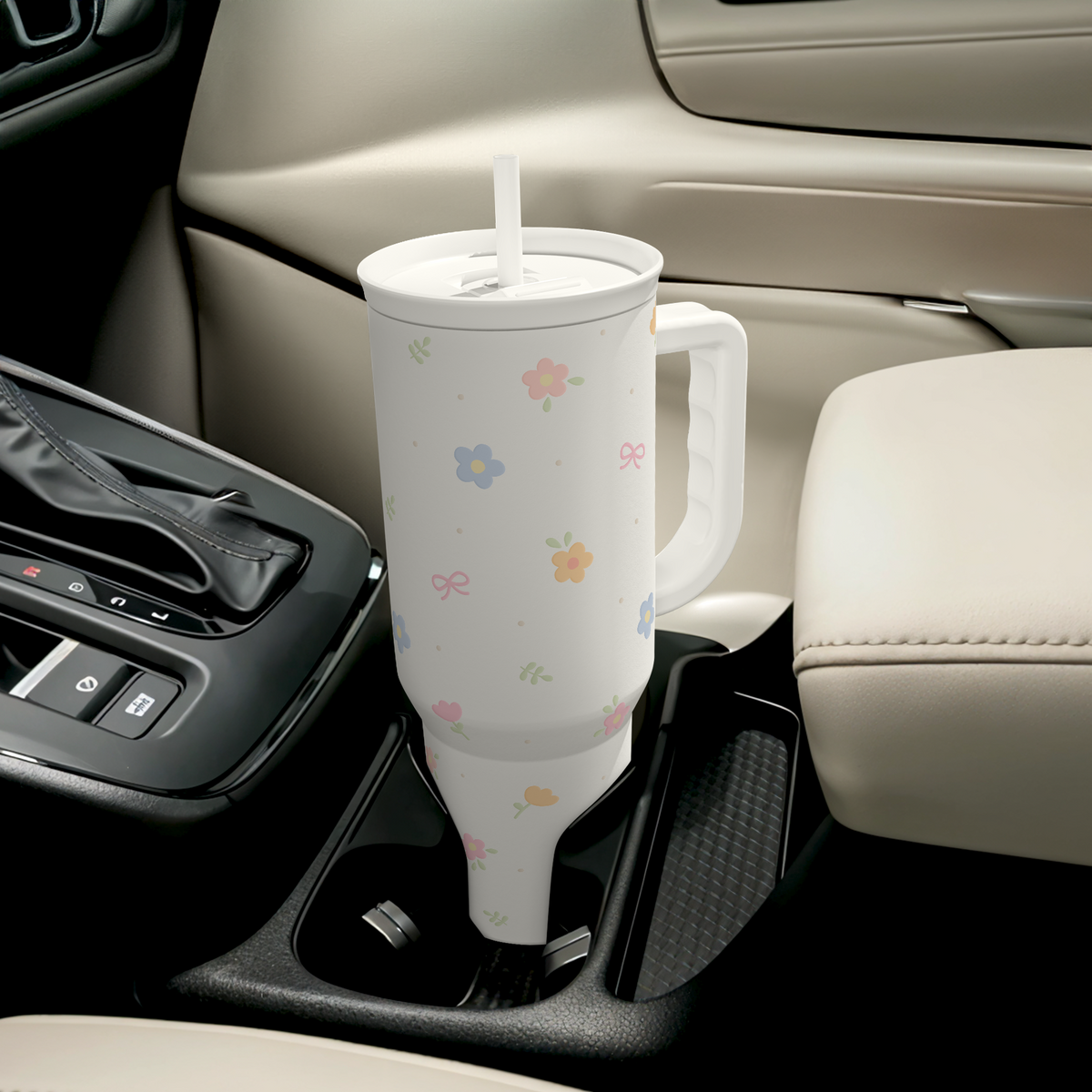 White floral 40oz tumbler with handle, straw, positioned in car cup holder