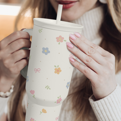 White floral 40oz tumbler with straw and handle, held by hands