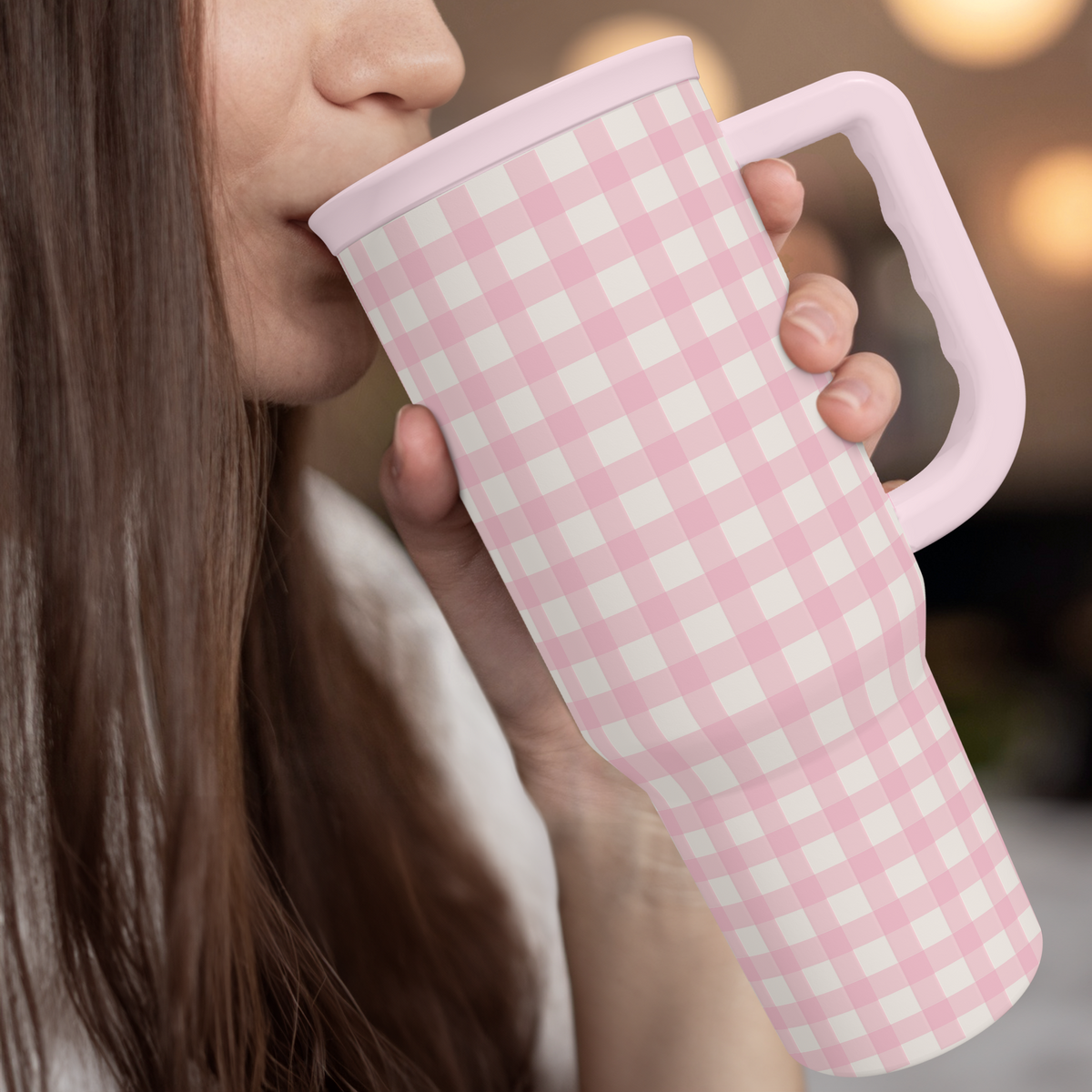 Pink gingham 40oz tumbler with straw, held near mouth