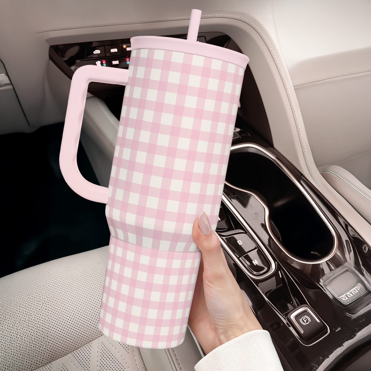 Pink gingham tumbler with large side handle and straw in car cup area