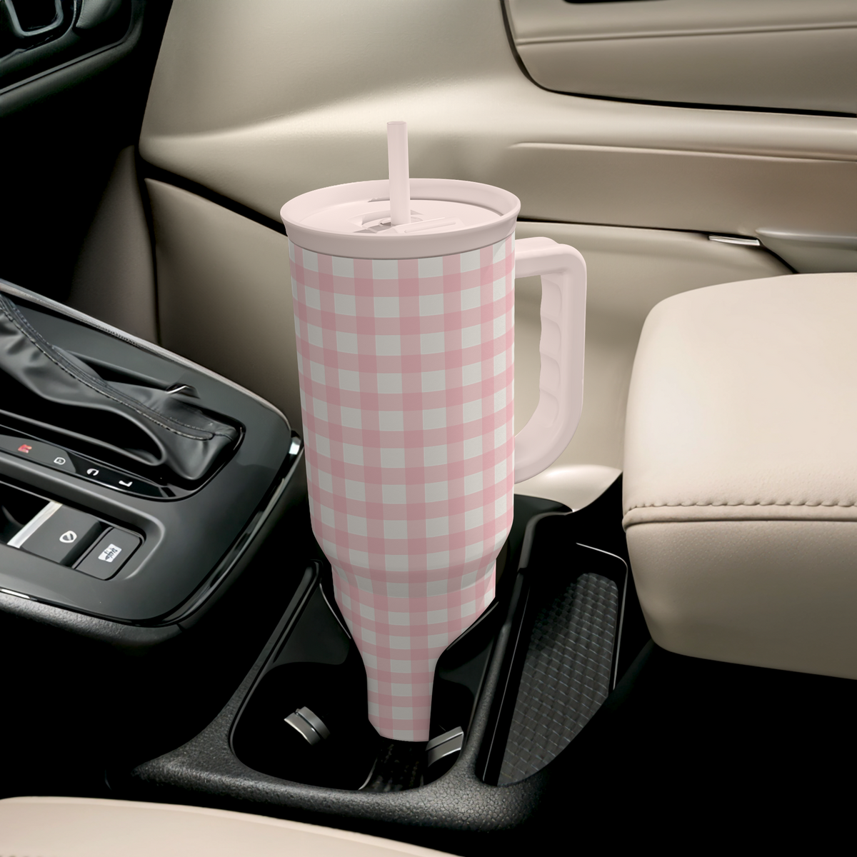 Pink gingham tumbler with side handle and straw in car console