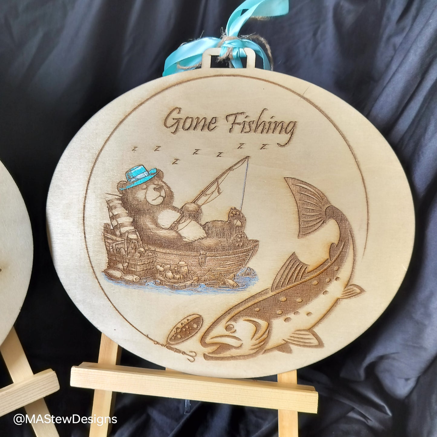 Round wood wall hanger with 'Gone Fishing' engraved fishing boat and fish, blue ribbon