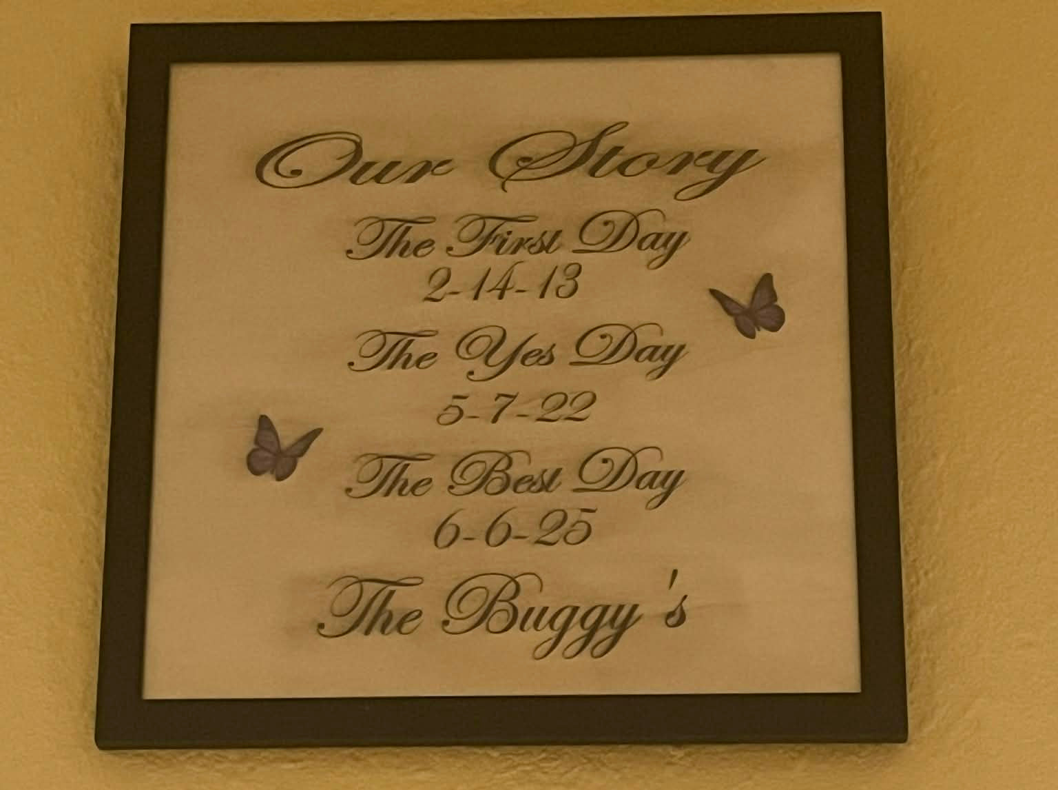 Framed plaque with special dates and 'Our Story' text on a wall.