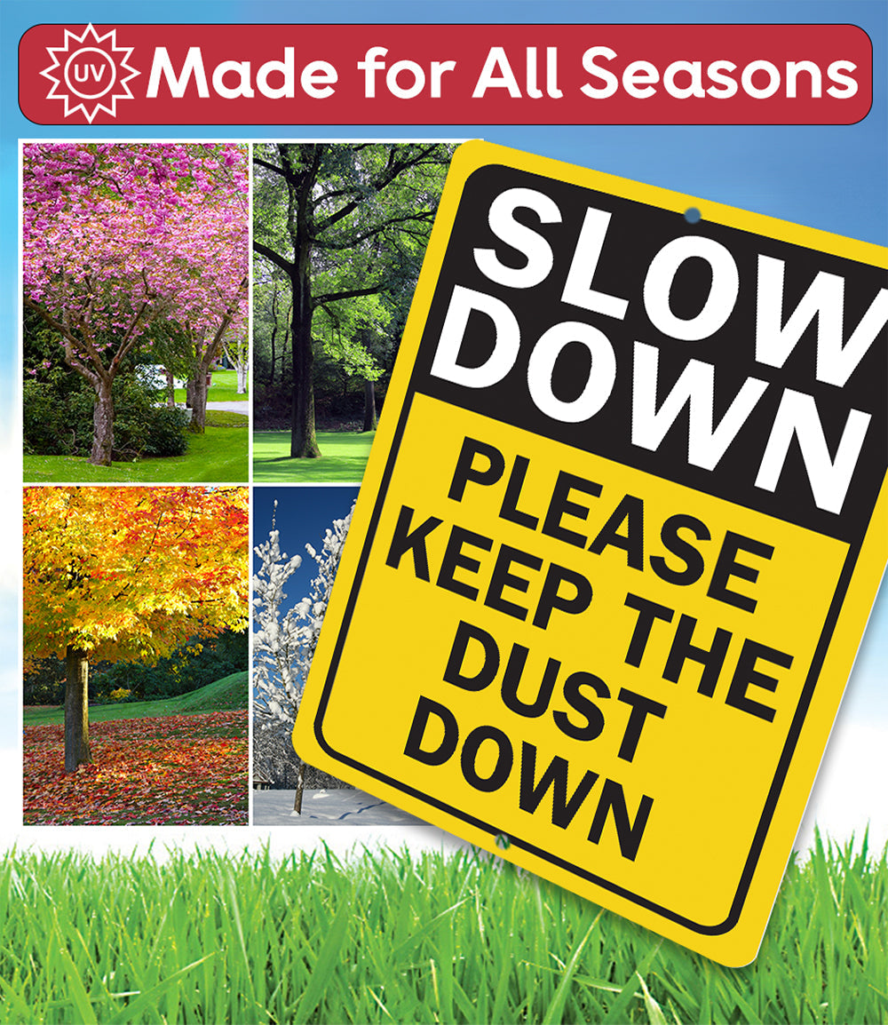 Tilted yellow metal sign with “SLOW DOWN” and “PLEASE KEEP THE DUST DOWN” text