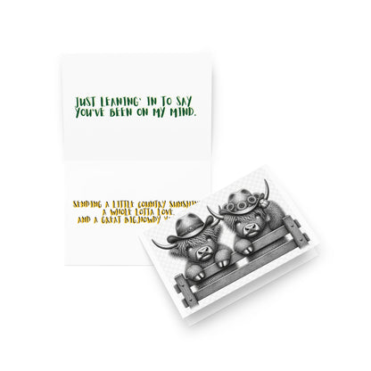 Open western greeting card with gray highland cow illustration and printed message inside
