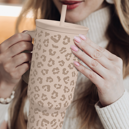 Leopard-print 40 oz tumbler with handle and straw, beige tan spots held by hands