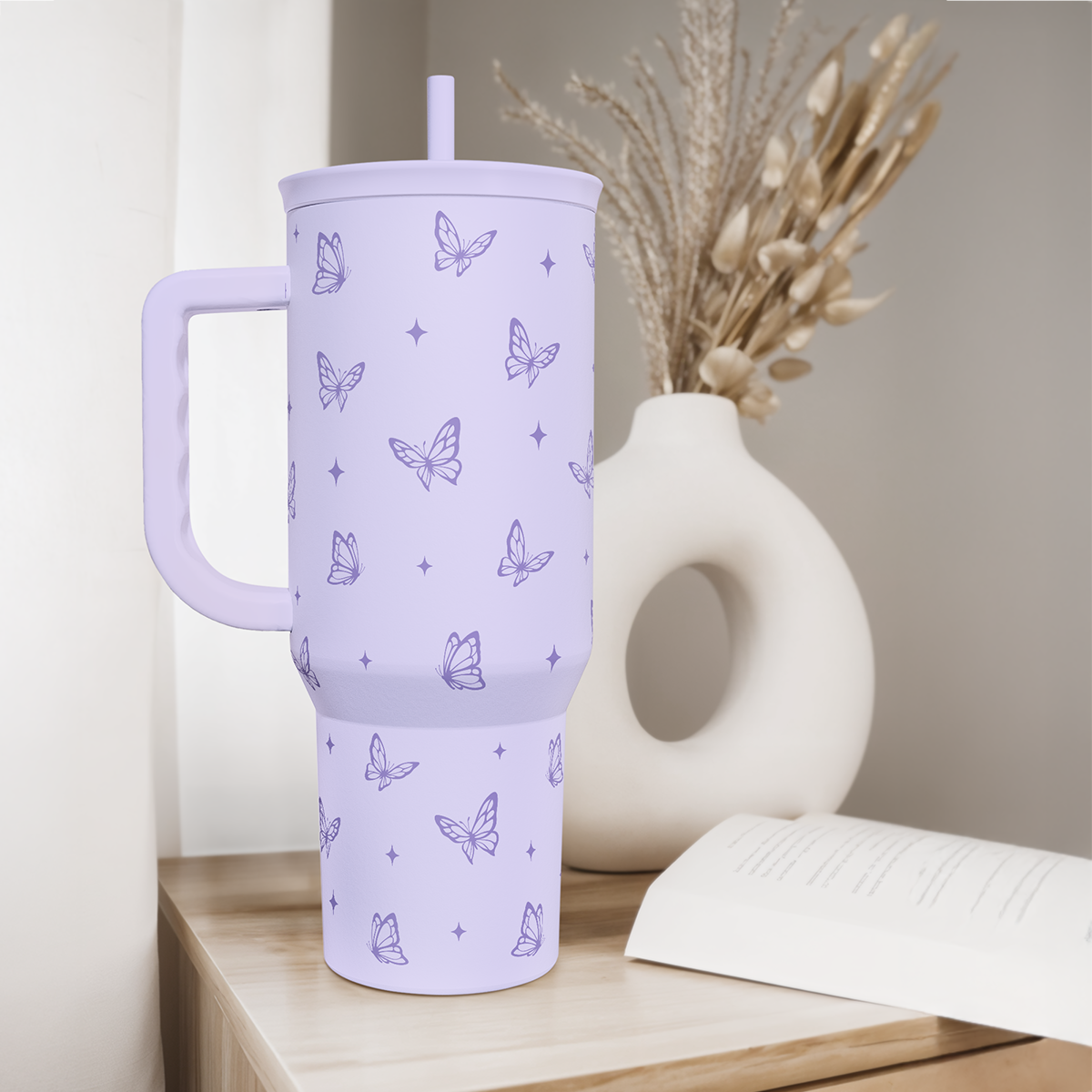 Lilac 40oz tumbler with handle and straw, butterfly pattern, on a wooden shelf.