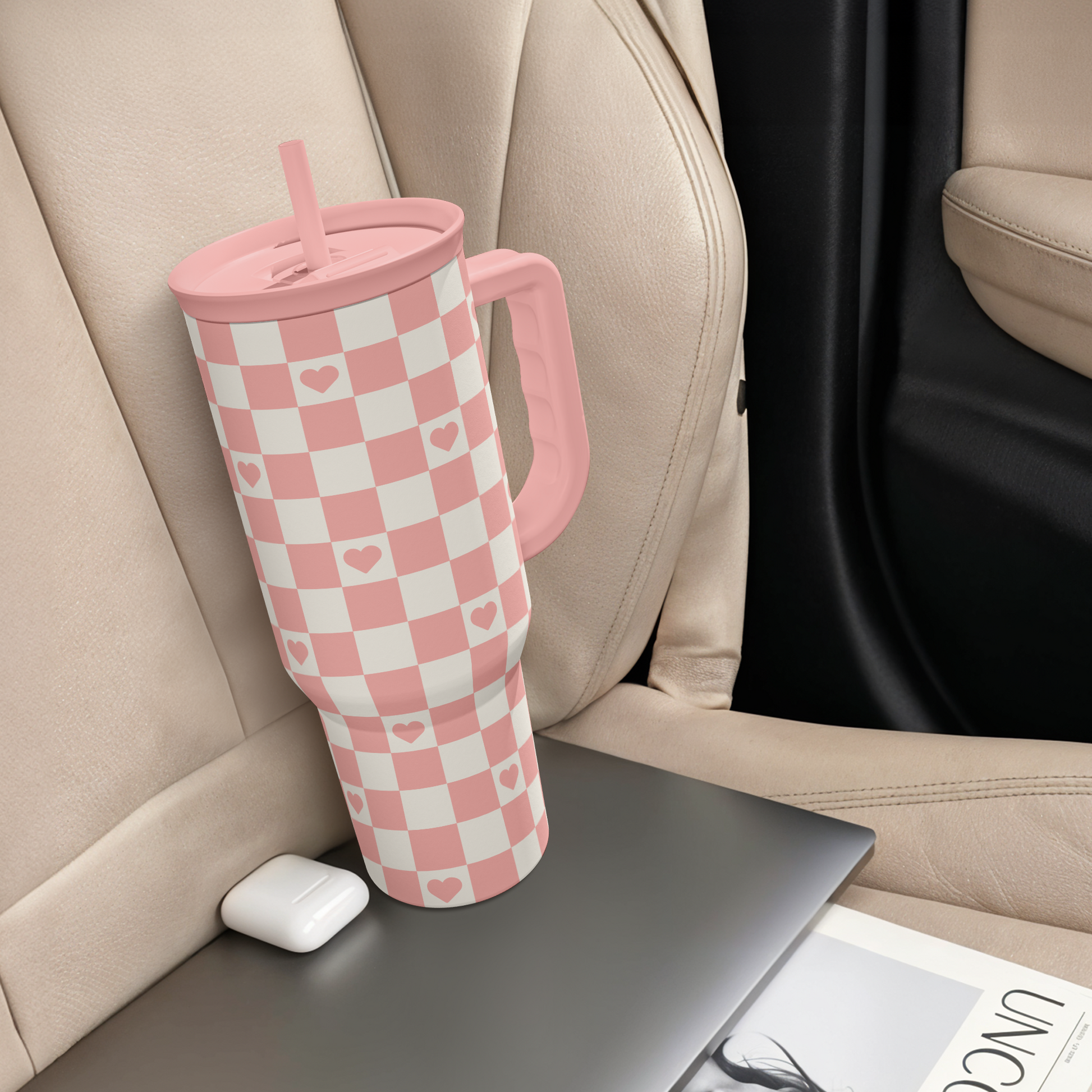 Coral checker heart tumbler with handle and straw lid, standing near seat