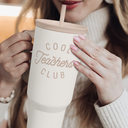 White tumbler with straw and “Cool Teachers Club” logo, held in hands