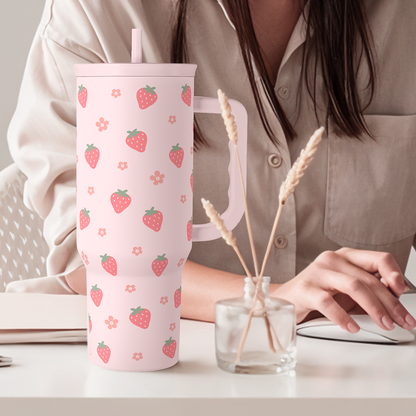 Pink strawberry-pattern 40oz tumbler with straw on table beside drink container