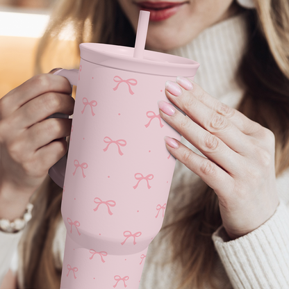 Pink bow-pattern tumbler with straw, held by two hands