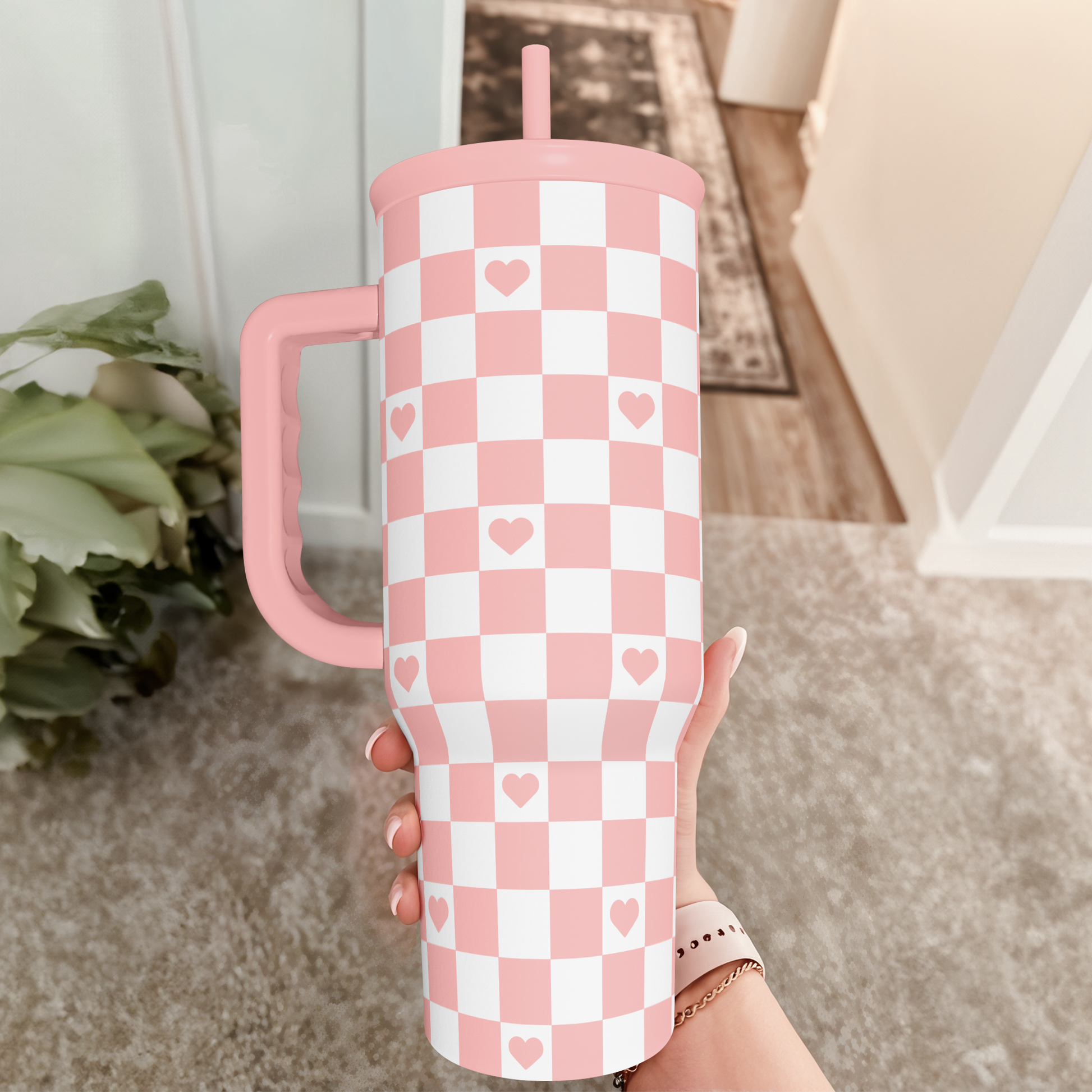 Coral checker heart tumbler with handle and pink straw lid, held upright