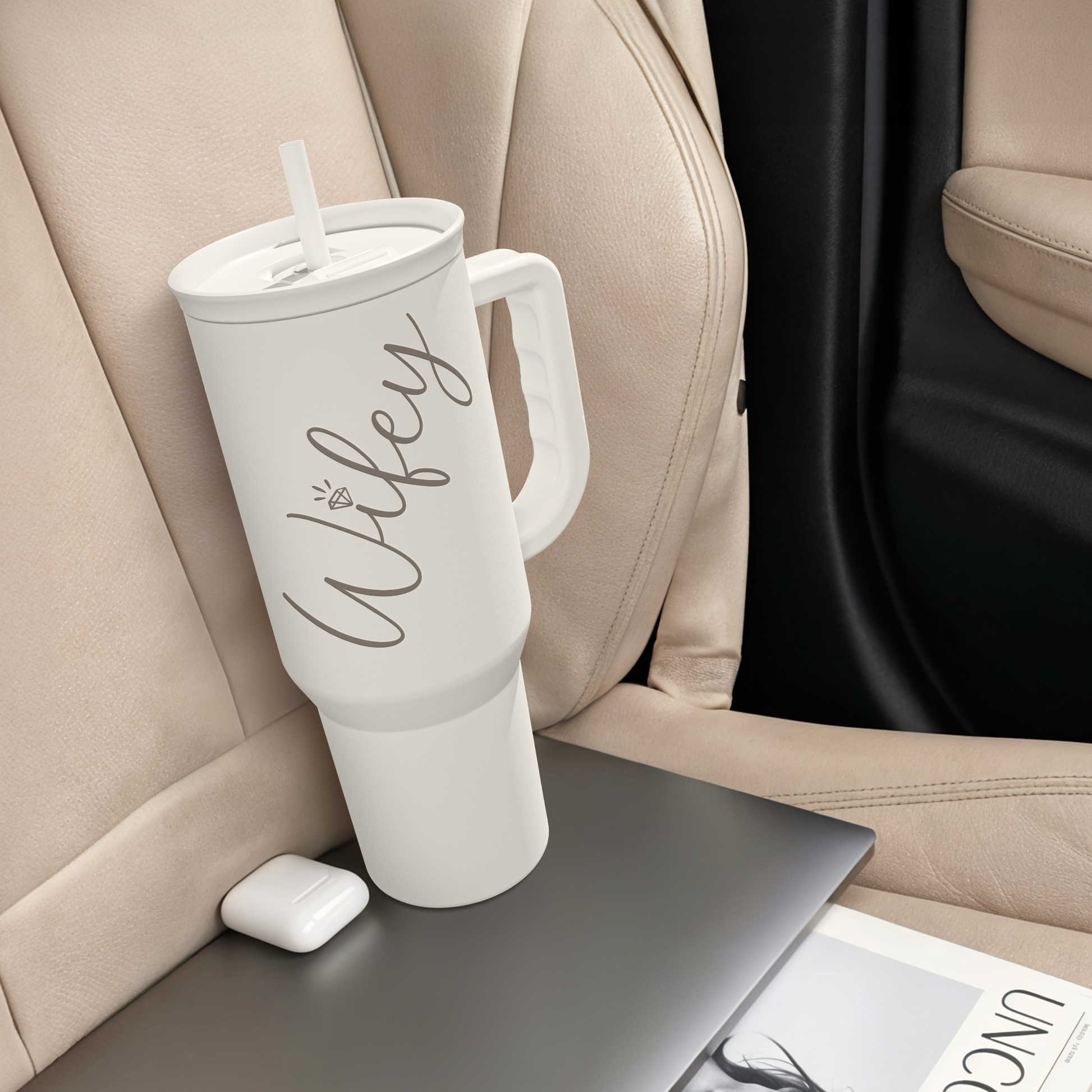 White tumbler with handle and straw, wife print, resting in a car seat