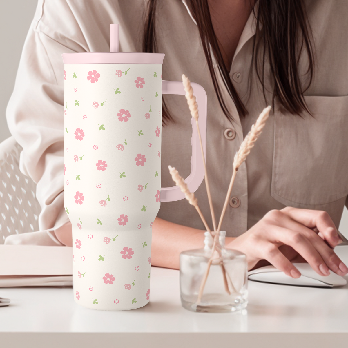 Pink floral 40oz tumbler with straw lid standing on a table