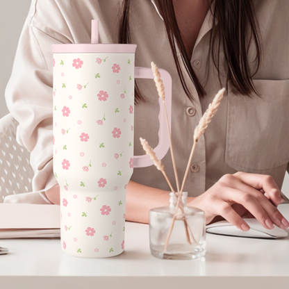 Pink floral 40oz tumbler with straw lid standing on a table