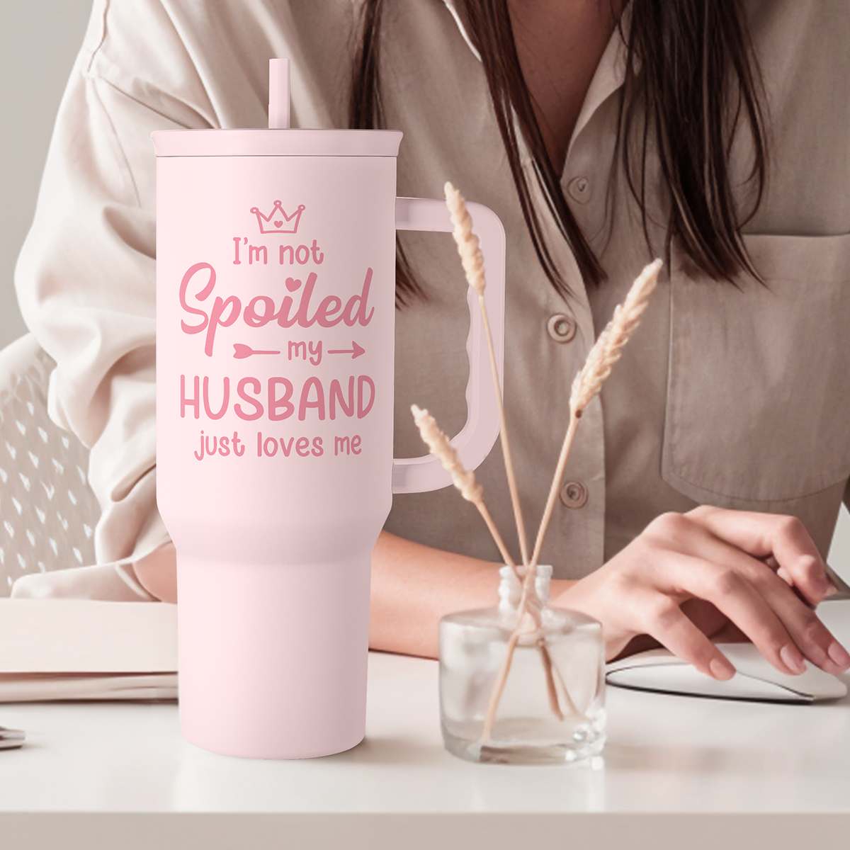 Pink tumbler with straw and handle; “I’m not Spoiled my HUSBAND” slogan on front