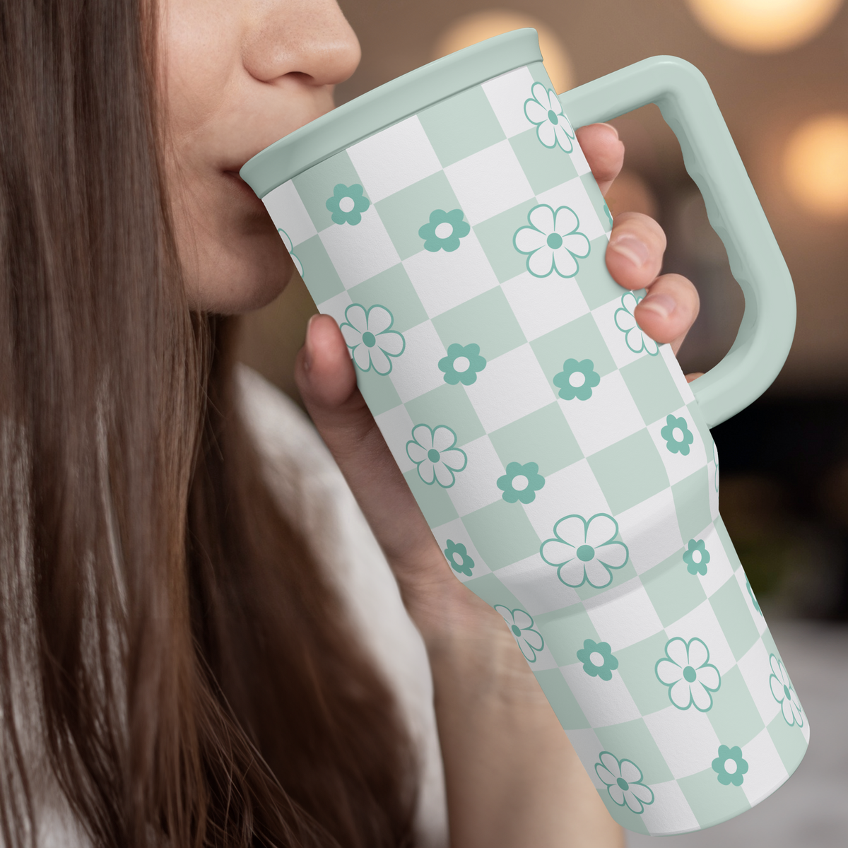Woman sipping from 40oz mint checker daisy tumbler with handle and clear straw