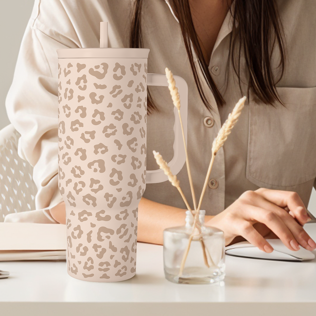 Leopard-print 40 oz tumbler with handle and straw, beige tan spots on desk