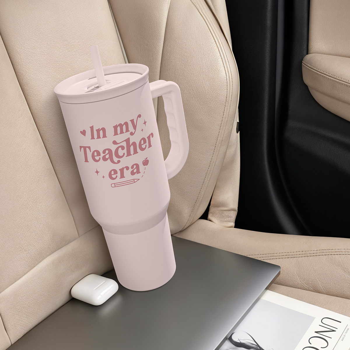 Pink 40oz insulated tumbler with handle and straw, placed in a car seat