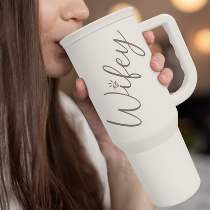 White slide-lid tumbler with handle and straw, wife print, held near the mouth