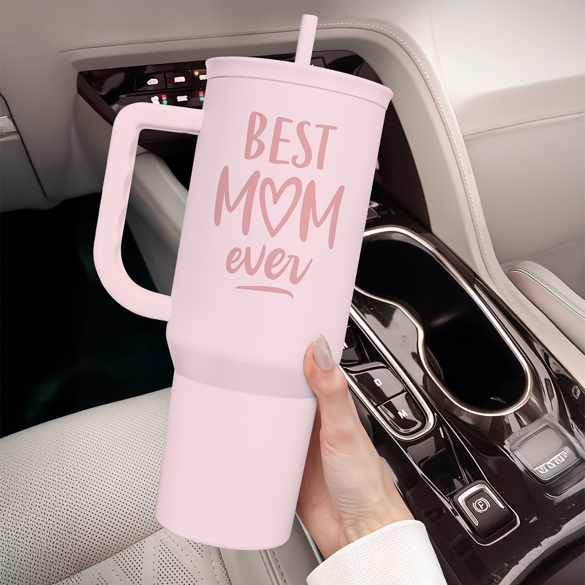 Pink 40oz tumbler with handle, 'Best Mom ever' print, held in a car cupholder