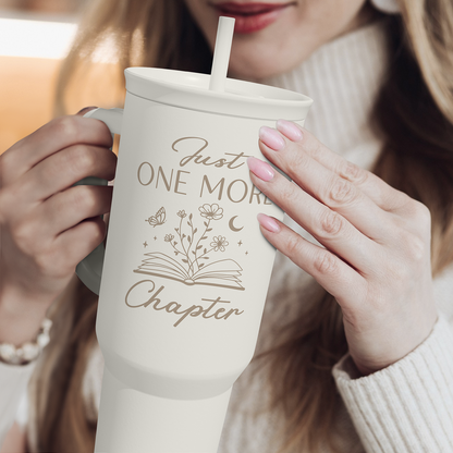 40oz white tumbler with book-themed print, straw and side handle held by hands