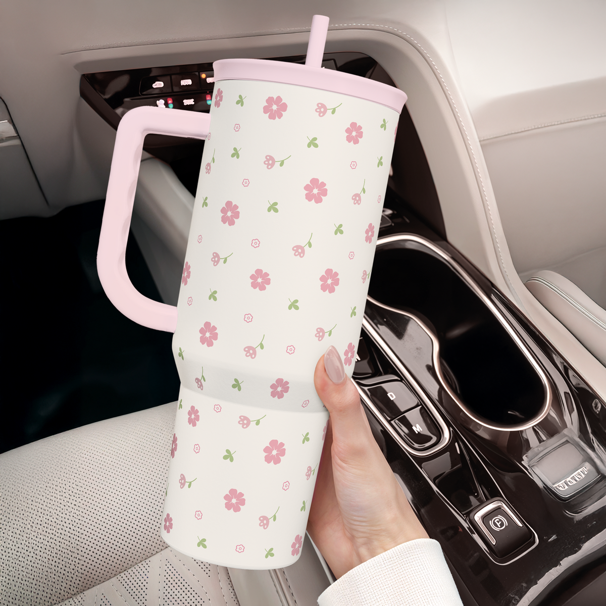 Pink floral 40oz tumbler with handle and straw positioned in car cup holder