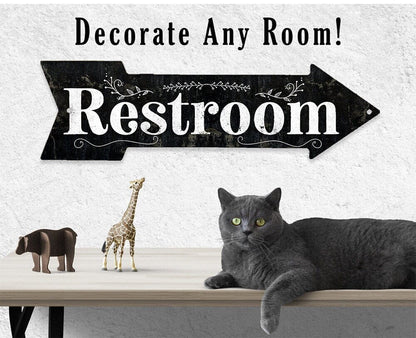 Restroom directional arrow metal sign above wall shelf with decor items