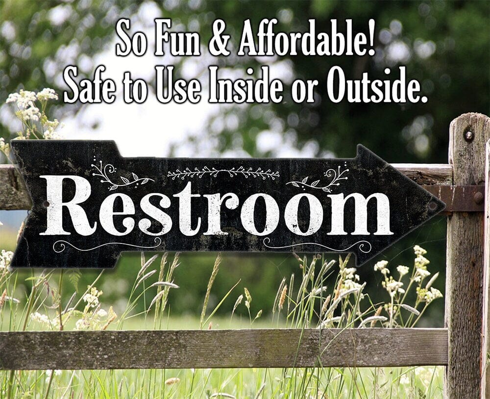 Restroom directional arrow metal sign with outdoor scene and grass below