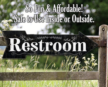 Restroom directional arrow metal sign with outdoor scene and grass below