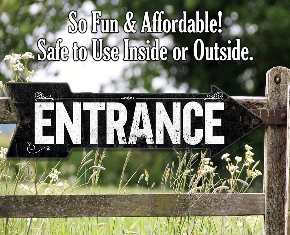 Black metal 'ENTRANCE' arrow sign with scroll details and two mounting holes