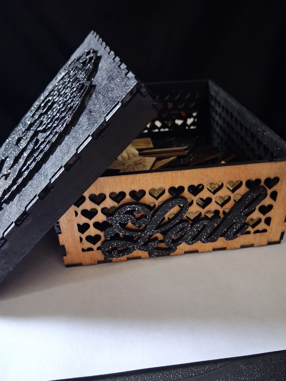 Open keepsake box with heart-pattern strip and glittery black cursive nameplate
