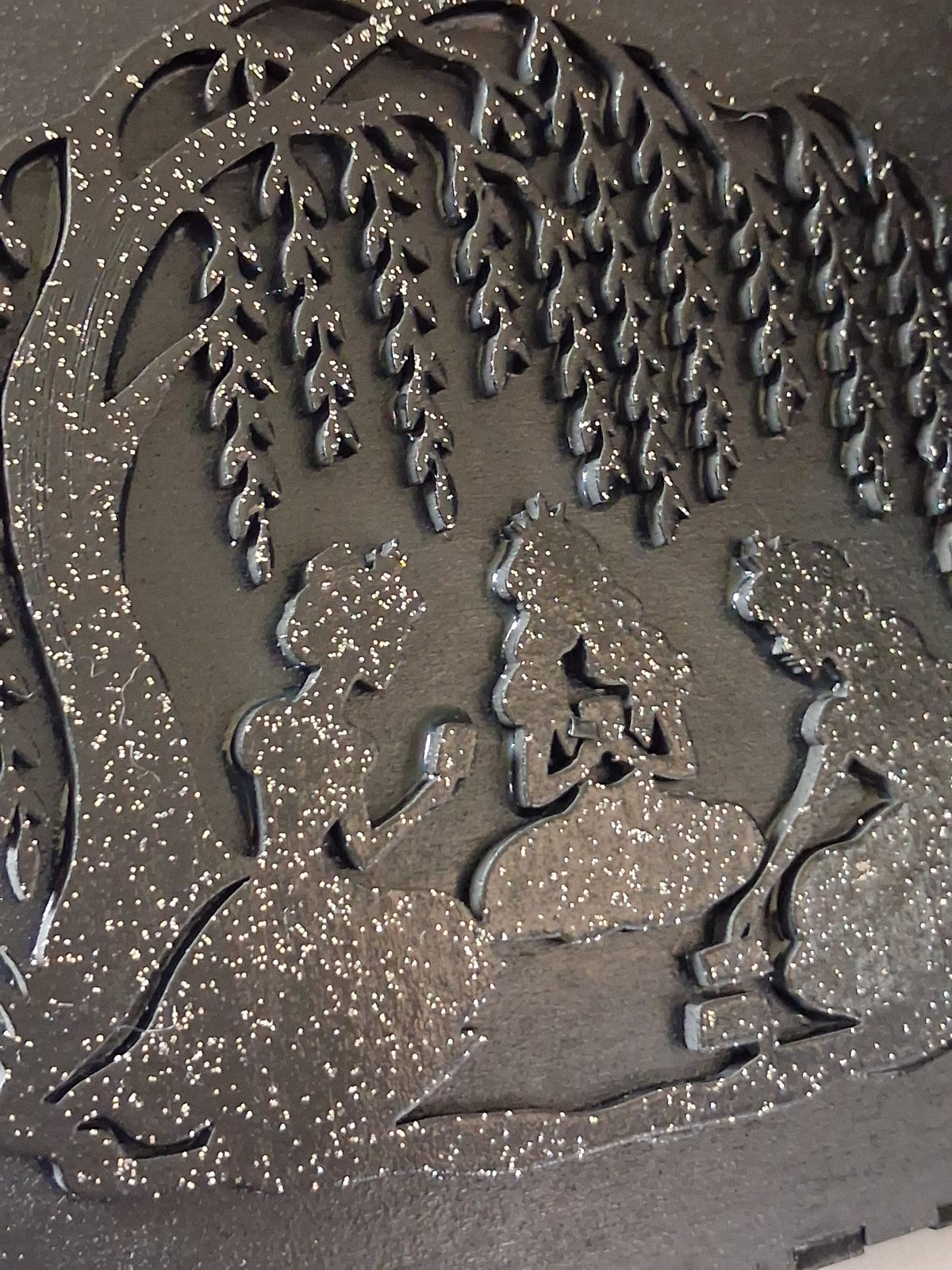 Close-up of dark felt lid with raised princess silhouette designs and glitter speckle