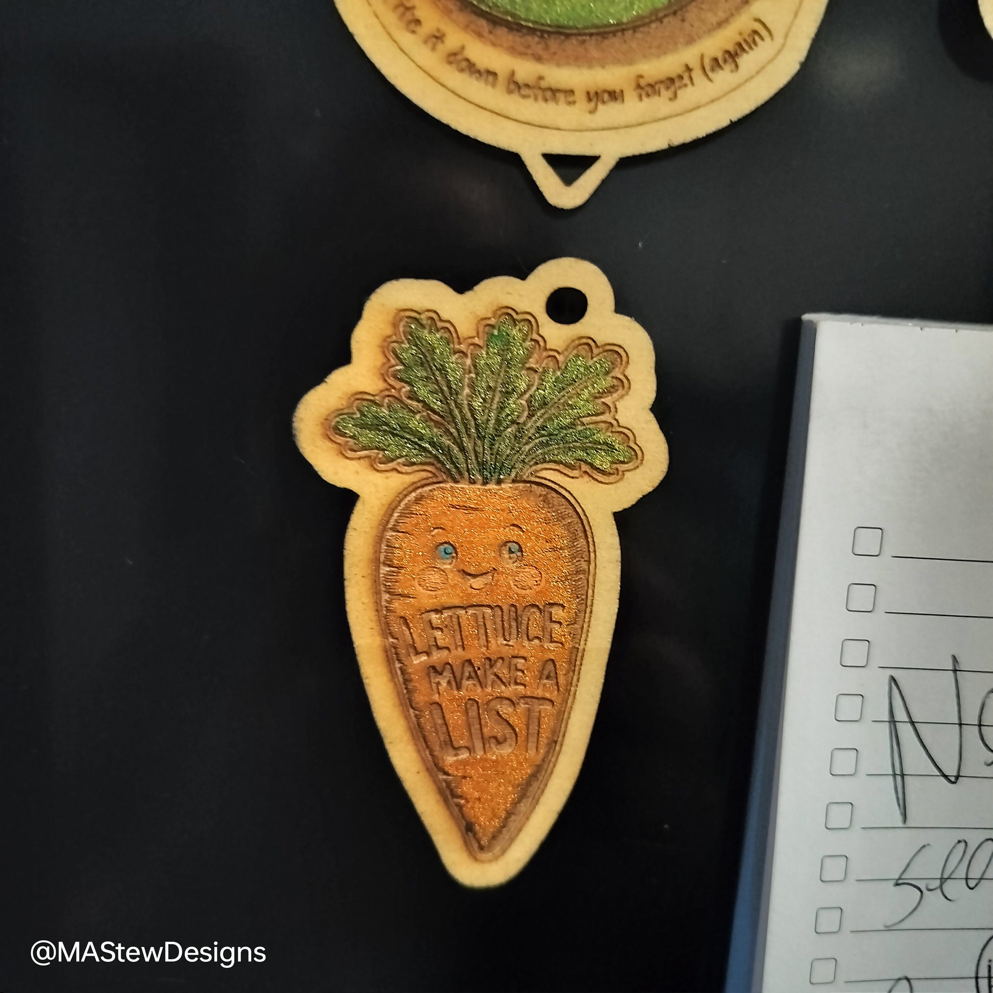 Carrot-themed magnetic pen keeper magnet with face and green leaves on fridge