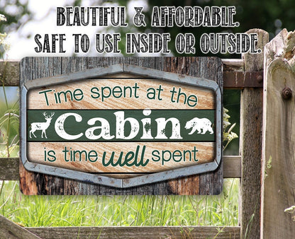Cabin metal sign outdoors with green panel, “Cabin” lettering, deer silhouettes, and border