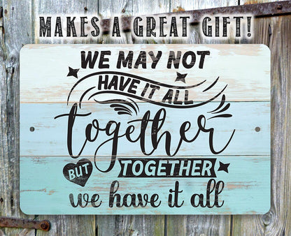 Light blue metal sign with quote: 'We may not have it all, but together we have it all'.