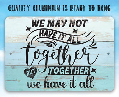 Light blue metal sign close-up with 'We may not have it all' and 'together' script.
